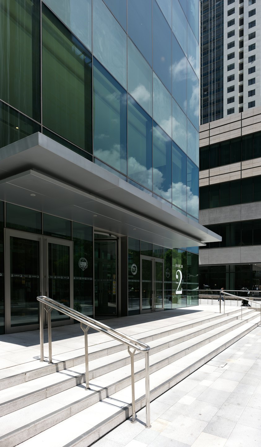 Entrada de un edificio de oficinas moderno con puertas de cristal y escalones de hormigón.